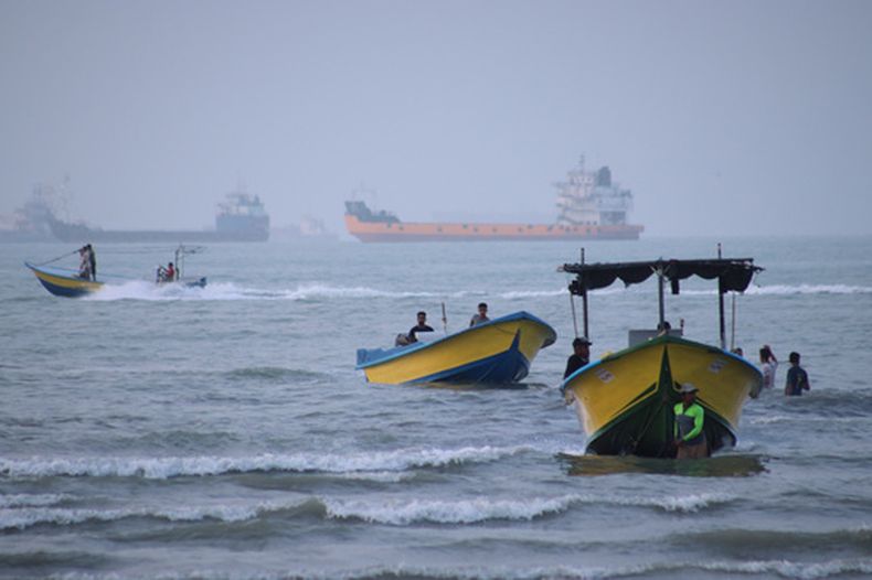 Pequeñas embarcaciones llegan a la costa mientras mercantes y otros buques comerciales parecen fondeados en el estrecho de Ormuz, ante la costa de Bandar Abbas, Irán, el 27 de julio de 2026. (Razieh Poudat/ISNA via AP)