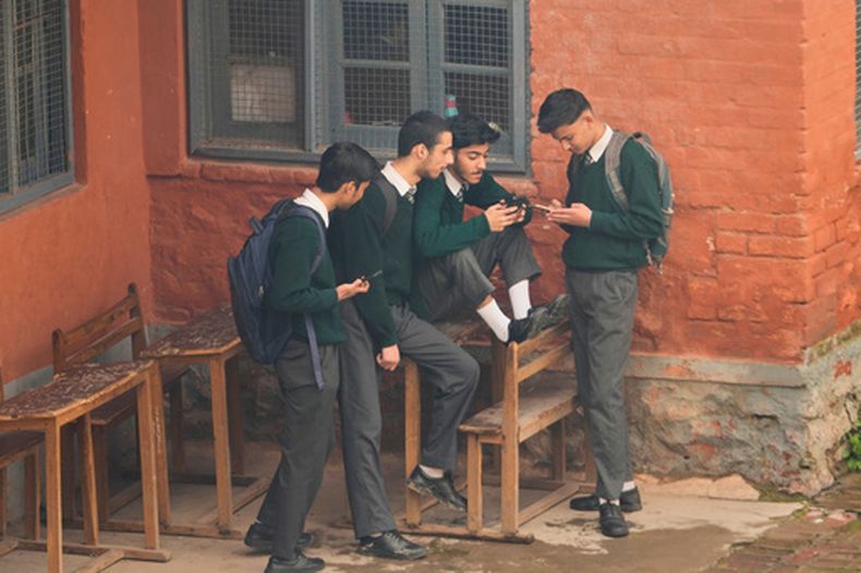 Varios estudiantes revisan sus teléfonos celulares en un complejo escolar de Srinagar, en la parte de Cachemira controlada por India, el jueves 9 de abril de 2026. (AP Foto/Mukhtar Khan)