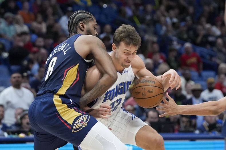 El alero del Magic de Orlando Franz Wagner (22) lucha contra el alero de los Pelicans de Nueva Orleáns Naji Marshall (8) en la segunda mitad de un partido de baloncesto de la NBA en Nueva Orleáns, el miércoles 3 de abril de 2024. El Magic ganó 117-108. (AP Foto/Gerald Herbert)