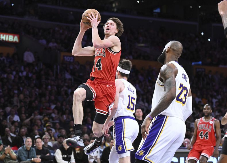 El alero de los Bulls de Chicago Matas Buzelis (14) anota una canasta frente al alero de los Lakers de Los Ángeles LeBron James (23) en la primera mitad de un partido de baloncesto de la NBA el sábado 22 de marzo de 2025, en Los Ángeles. (AP Foto/Wally Skalij)