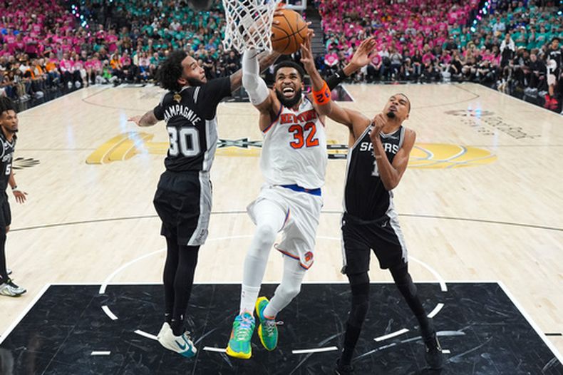 Karl-Anthony Towns, de los Knicks de Nueva York, encesta entre Victor Wembanyama y Julian Champagnie, de los Spurs de San Antonio, el miércoles 3 de junio de 2026 (AP Foto/Eric Gay)