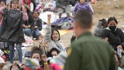 Mujeres muestran sus pulseras con la esperanza de ser elegidas por los agentes de la Patrulla Fronteriza de Estados Unidos para que su solicitud de asilo se atendida, luego de una espera de días entre los dos muros fronterizos, el viernes 12 de mayo de 2023, en San Diego. (AP Foto/Gregory Bull)
