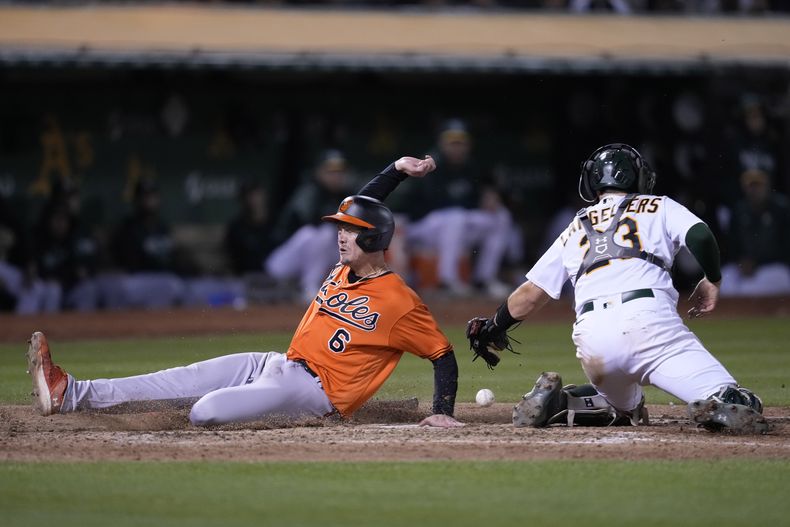Ryan Mountcastle, de los Orioles de Baltimore, anota frente a Shea Langeliers, cátcher de los Atléticos de Oakland, en el décimo inning del juego del sábado 19 de agosto de 2023 (AP Foto/Eric Risberg)