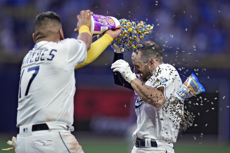 El mexicano Isaac Paredes, de los Rays de Tampa Bay, arroja goma de mascar y semillas de girasol a Brandon Lowe, quien bateó el sencillo del triunfo ante los Rockies de Colorado, el miércoles 23 de agosto de 2023 (AP Foto/Chris OMeara)