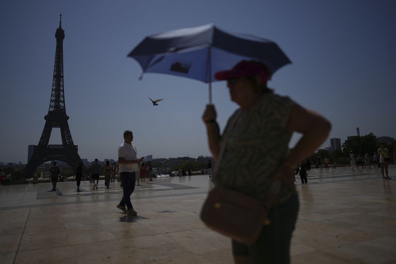 ARCHIVO - Varias personas caminan por la plaza de Trocadero, cerca de la torre Eiffel, en plena ola de calor, el 2 de julio de 2025, en París. (AP Foto/Christophe Ena, archivo)