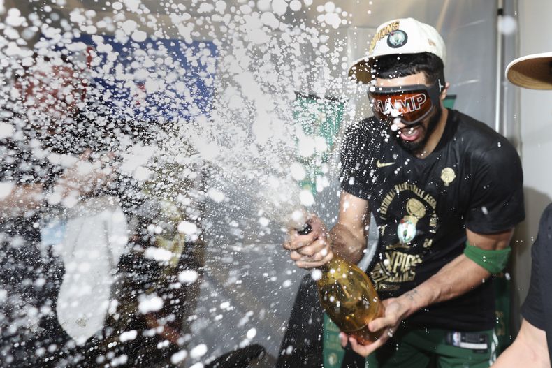 Jayson Tatum, de los Celtics de Boston, lanza champaña al celebrar la victoria sobre los Mavericks de Dallas en el quinto partido de las Finales de la NBA, el lunes 17 de junio de 2024 (Elsa/Pool Photo via AP)