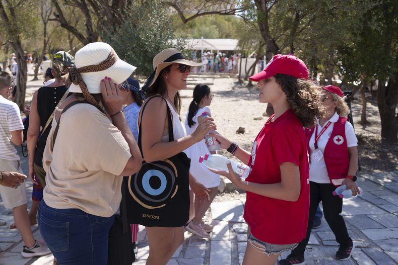 En esta imagen de archivo, una voluntaria de Cruz Roja reparte agua entre los turistas al pie de la Acrópolis durante un día de calor en Atenas, el 17 de julio de 2024. (AP Foto/Petros Giannakouris, archivo)