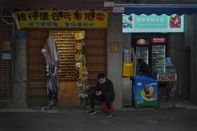 Un vendedor descansa afuera de su tienda de souvenirs en Xiamen, en el sureste de China, el 27 de diciembre de 2023. (AP Foto/Andy Wong)