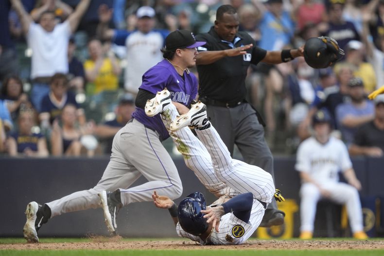 Joey Ortiz, abajo, de los Cerveceros de Milwaukee, rueda después de anotar carrera con un wild pitch durante la 10ma entrada del juego de béisbol de Grandes Ligas frente a los Rockies de Colorado, el domingo 29 de junio de 2025, en Milwaukee. (AP Foto/Aaron Gash)
