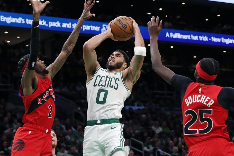 Jayson Tatum, de los Celtics de Boston, salta hacia la canasta entre Jalen McDaniels y Chris Boucher, de los Raptors de Toronto, el sábado 11 de noviembre de 2023 (AP Foto/Michael Dwyer)