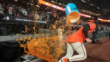 El dominicano Willy Adames, de los Gigantes de San Francisco, corre para evitar que su compañero Trent Harris lo empape con la hielera, tras la victoria sobre los Tigres de Detroit, el viernes 7 de agosto de 2026 (AP Foto/Jeff Chiu)