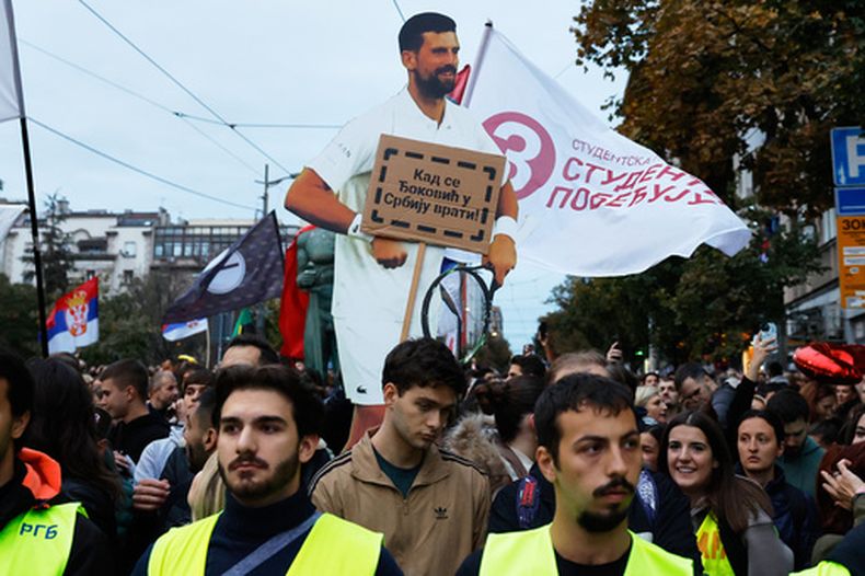 Un grupo de personas sostiene un cartel con la imagen del tenista serbio Novak Djokovic durante un acto de campaña de la lista opositora Student List – Students Win previo a las elecciones parlamentarias de Serbia, el jueves 22 de octubre de 2026, en Belgrado. (AP Foto/Marko Drobnjakovic)