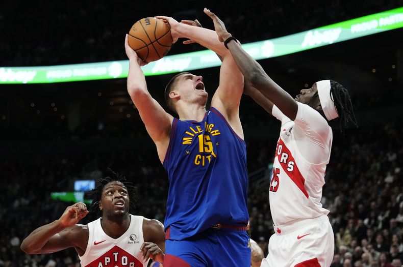 El serbio Nikola Jokic, de los Nuggets de Denver, trata de disparar frente a Chris Boucher, de los Raptors de Toronto, en el duelo del miércoles 20 de diciembre de 2023 (Frank Gunn/The Canadian Press via AP)
