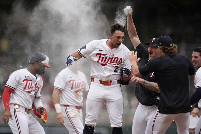 Brooks Lee de los Mellizos de Minnesota celebra con sus compañeros su toque remolcador de la victoria que llevó a la anotación de Byron Buxton en la novena ante los Rays de Tampa Bay el sábado 5 de julio del 2025. (AP Foto/Abbie Parr)