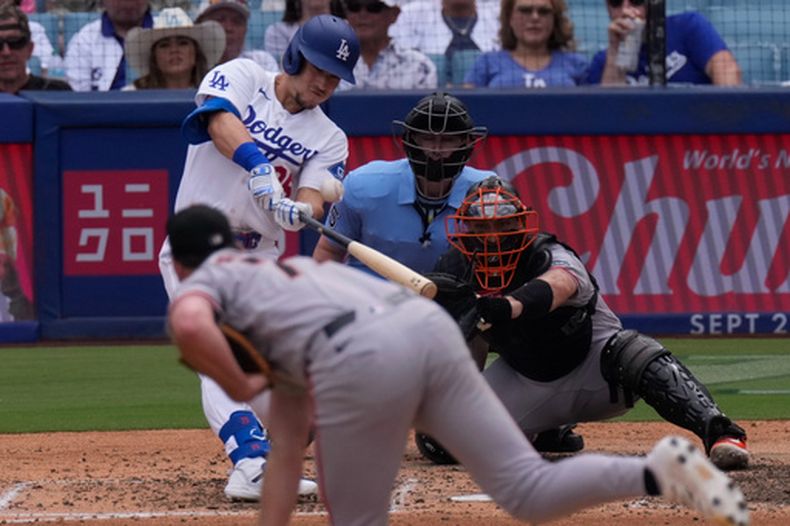 Tommy Edman, al bate, conecta un cuadrangular solitario mientras Carson Seymour, en primer plano, lanzador de los Gigantes de San Francisco, y el receptor Andrew Knizner observa en la sexta entrada del juego de béisbol de Grandes Ligas, el domingo 20 de septiembre de 2026, en Los Ángeles. (AP Foto/Mark J. Terrill)