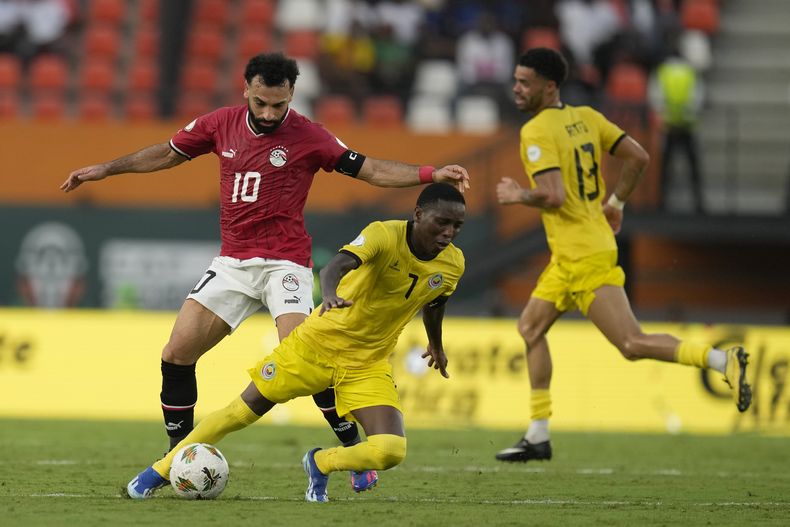 El mozambiqueño Elias Pelembe, a la derecha del egipcio Mohamed Salah durante el partido de fútbol del Grupo B de la Copa Africana de Naciones entre Egipto y Mozambique en Abiyán, Costa de Marfil, el domingo 14 de enero de 2024. (AP Foto/Themba Hadebe)