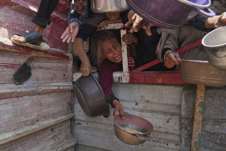 Varios palestinos luchan por obtener alimentos donados en una cocina comunitaria en Ciudad de Gaza, en el norte del enclave, el sábado 26 de julio de 2025. (AP Foto/Abdel Kareem Hana)