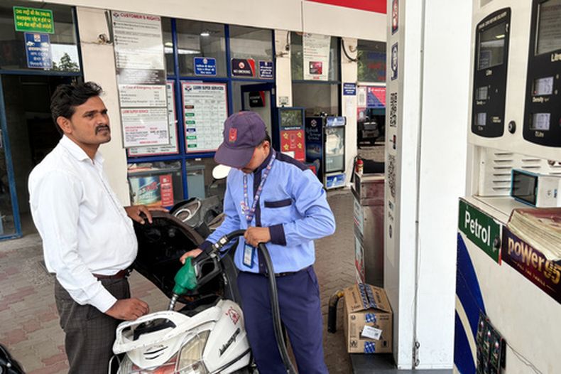 Un conductor controla el precio del combustible mientras un trabajador llena el depósito de su moto en una gasolinera en Nueva Delhi, India, el 15 de mayo de 2026. (AP Foto/Shonal Ganguly)