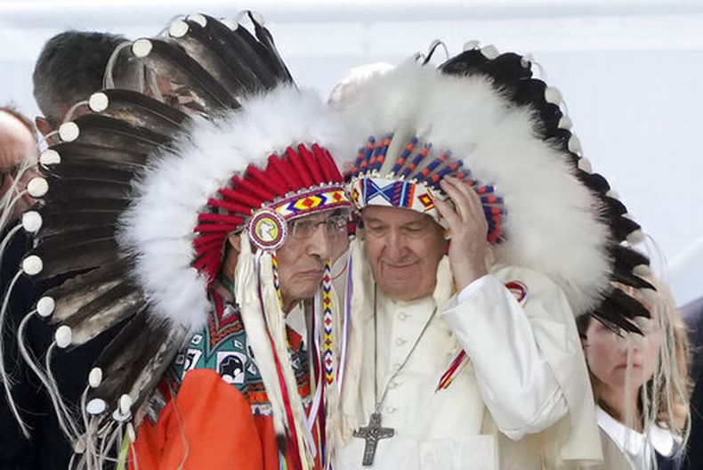 ARCHIVO - El papa Francisco se pone un tocado indígena durante una reunión con comunidades indígenas, incluidas de las primeras naciones, metis e inuit, en la iglesia católica de Nuestra Señora de los Siete Dolores en Maskwacis, cerca de Edmonton, Canadá, el lunes 25 de julio de 2022. (AP Foto/Gregorio Borgia, Archivo)