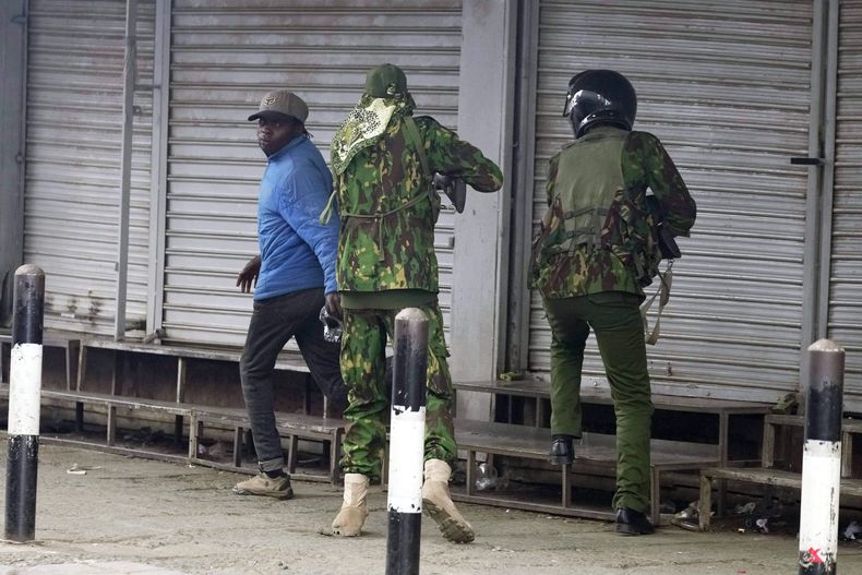 Un policía keniano, centro, se prepara para disparar al vendedor ambulante Boniface Kariuk, izquierda, durante una protesta en Nairobi, Kenia, el martes 17 de junio de 2025. (Foto AP/Brian Inganga)