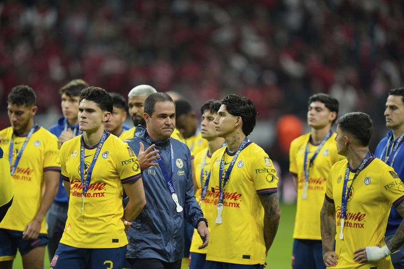 Andre Jardine, tercero de izquierda a derecha, entrenador de las Águilas del América, y sus jugadores, observan desde el campo la premiación del equipo campeón de la Liga MX después de recibir sus medallas de subcampeón, luego de perder 0-2 ante los Diablos de Toluca en el partido de vuelta de la Final de la Liga MX, el domingo 25 de mayo de 2025, en el estadio Nemesio Diez, en Toluca, México. (AP Foto/Fernando Llano)