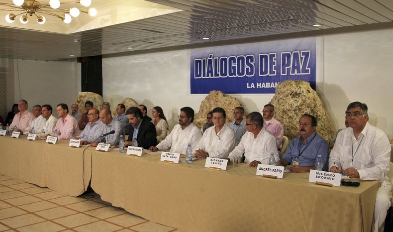 Representantes de la delegaci&oacute;n de negociadores del gobierno de Colombia, del centro a la izquierda, y representantes de las Fuerzas Armadas Revolucionarias de Colombia (FARC) a la derecha de la mesa, emiten un comunicado conjunto en La Habana, Cub