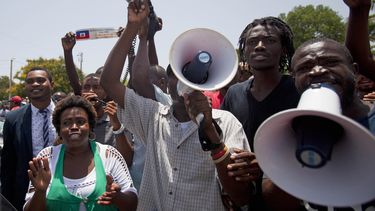 Manifestantes corean consignas contra Francia mientras el presidente francés Francois Hollande pronuncia un discurso frente al Palacio Nacional en Puerto Príncipe, Haití, el 12 de mayo de 2015. (AP Foto/Dieu Nalio Chery, File)