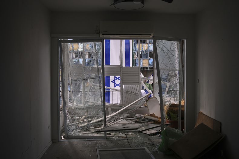 Una bandera israelí cuelga fuera de un apartamento dañado dos días después de ser impactado por un misil lanzado por Irán, en Ramat Gan, Israel, el sábado 21 de junio de 2025. (AP Foto/Ohad Zwigenberg)
