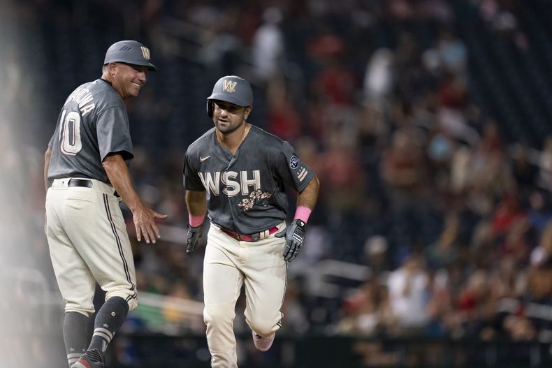 Jake Alu, derecha, de los Nacionales de Washington, celebra con el coach de tercera base, Gary Disarcina, izquierda, después de batear jonrón durante la octava entrada del juego de béisbol en contra de los Atléticos de Oakland, el viernes 11 de agosto de 2023, en Washington. (AP Foto/Stephanie Scarbrough)