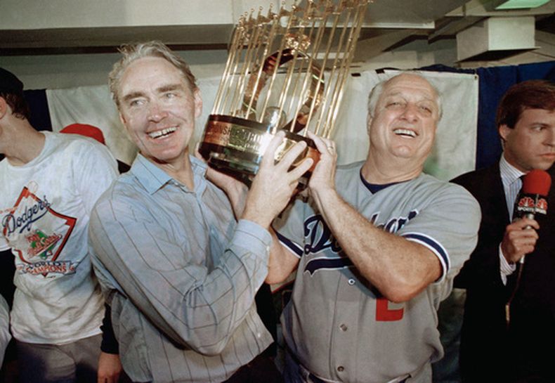 ARCHIVO - El mánager Tommy Lasorda (derecha) y el vicepresidente Fred Claire, de los Dodgers de Los Ángeles, alzan el trofeo de la Serie Mundial tras vencr a los Atléticos de Oakland, el 20 de octubre de 1987. (AP Foto/Bill Beattie)