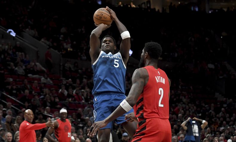El base de los Timberwolves de Minnesota Anthony Edwwards lanza sobre el centro de los Trail Blazers de Portland Deandre Ayton durante la primera mitad del juego de baloncesto de la NBA, en Portland, Oregon, el martes 13 de febrero de 2024. (AP Foto/Steve Dykes)