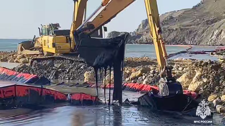 En esta fotografía tomada de un video difundido por el Servicio de Prensa del Ministerio de Emergencias Ruso el viernes 17 de enero de 2025, una excavadora retira crudo cerca del petrolero dañado Volgoneft-239 del que el crudo sigue saliendo al mar cerca del puerto Taman, en la región de Krasnodar del sur de Rusia. (Servicio de Prensa del Ministerio de Emergencias Ruso vía AP)