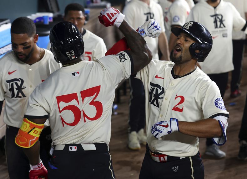 Marcus Semien (2) de los Rangers de Texas celebra junto a su compañero el cubano Adolis García (53) ante los Rojos de Cincinnati durante la octava entrada del juego de béisbol el viernes 26 de abril de 2024, en Arlington, Texas. (AP Foto/Richard W. Rodriguez)