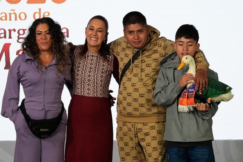 La presidenta mexicana Claudia Sheinbaum posa con el Pato Merlín, junto con su dueña Carla Gómez, el lunes 22 de junio de 2026 en Palacio Nacional. En la foto aparecen también los hijos de Gómez, Carlos y Christian, quien sostiene al pato (AP Foto/Marco Ugarte)
