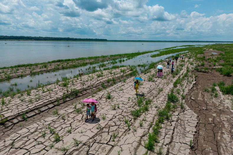 ARCHIVO - Personas caminan por una zona del río Amazonas que muestra signos de sequía en Santa Sofía, en las afueras de Leticia, Colombia, el 20 de octubre de 2024. (AP Foto/Iván Valencia/Archivo)