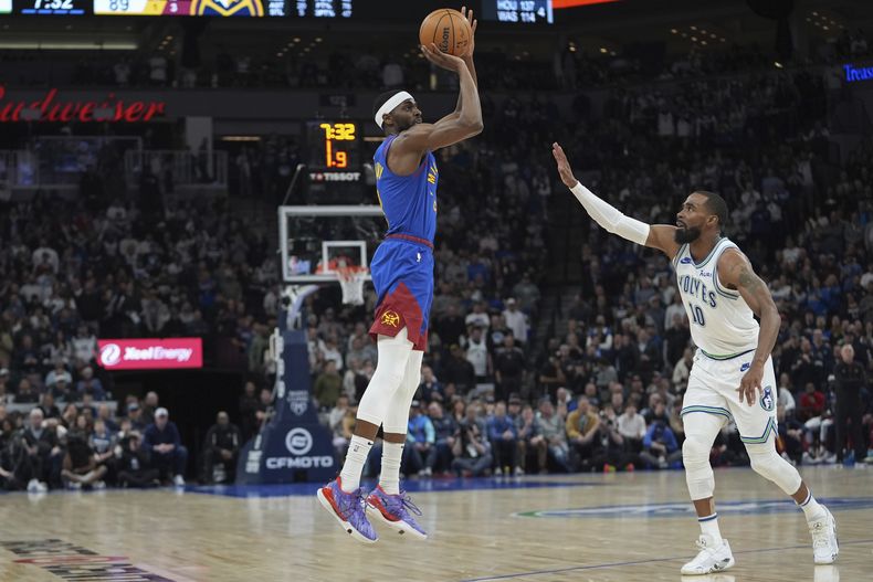 El alero de los Nuggets de Denver Justin Holiday lanza el balón sobre el base de los Timberwolves de Minnesota Mike Conley en el encuentro de la NBA del martes 19 de marzo del 2024. (AP Foto/Abbie Parr)