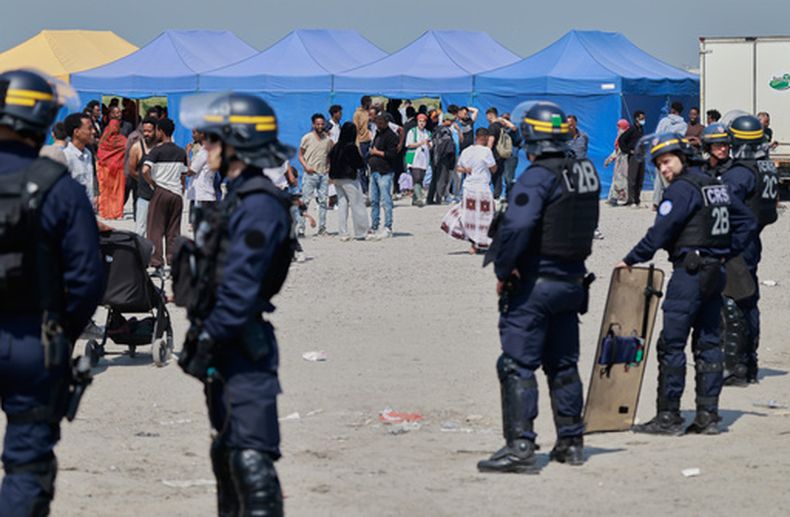 Agentes de policía llevan a cabo una redada en un campamento de migrantes que quieren cruzar el canal de la Mancha hacia Reino Unido, cerca de Dunkerque, en el norte de Francia, el 27 de mayo de 2026. (AP Foto/Jean-Francois Badias)