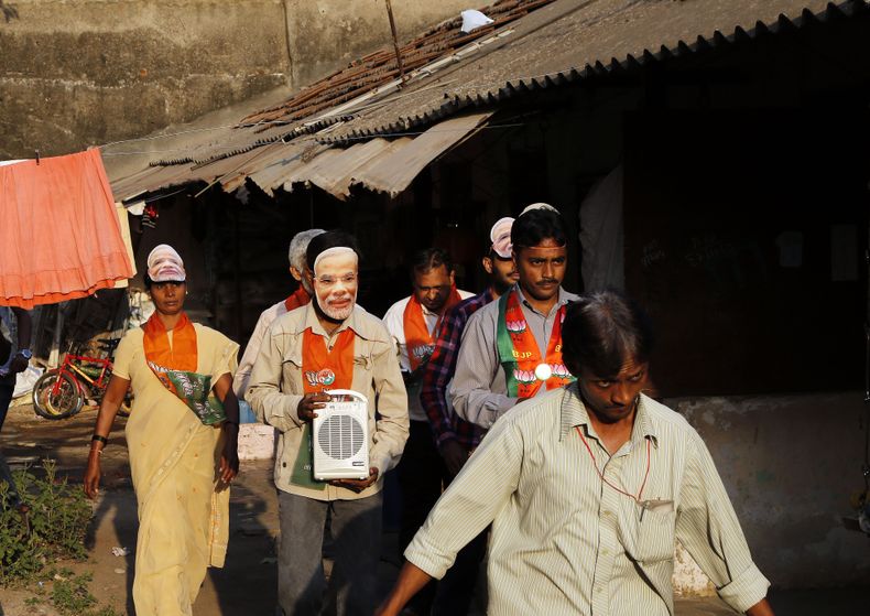 Partidarios del principal partido de la oposici&oacute;n en India, el Bharatiya Janata, participan en un acto con motivo de los comicios en Mumbai, India, el mi&eacute;rcoles 9 de abril de 2014. Uno de ellos, al centro, lleva puesta una m&aacute;scara de