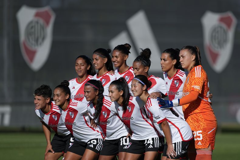 La japonesa Ichika Egashira (primera de la derecha en la fila inferior) posa junto a su equipo River Plate ante de enfrentarse a su clásico rival Boca Juniors en la primera jornada de la liga de fútbol femenino de Argentina en Ezeiza, suburbio al oeste de Buenos Aires, Argentina, el domingo 10 de marzo de 2024. Egashira es parte de un fenómeno creciente de jugadoras extranjeras que buscan darle impulso a los clubes de la primera división local recientemente profesionalizados. (AP Foto/Natacha Pisarenko)