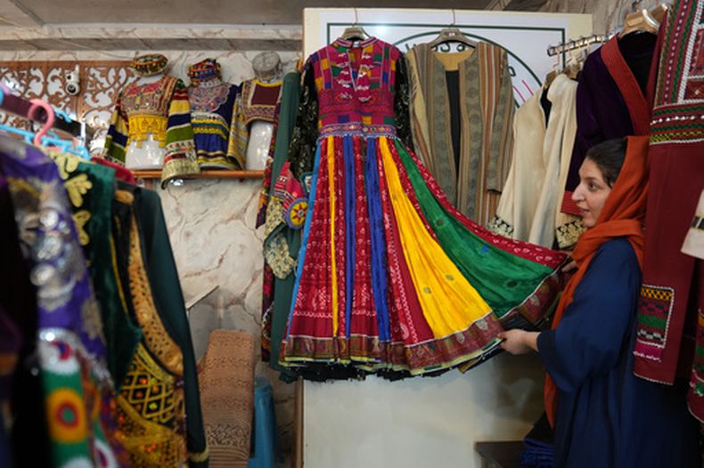 Tahmina Mangal muestra un vestido tradicional afgano en su tienda de ropa en Kabul, Afganistán, el domingo 4 de octubre de 2026. (AP Foto/Siddiqullah Alizai)