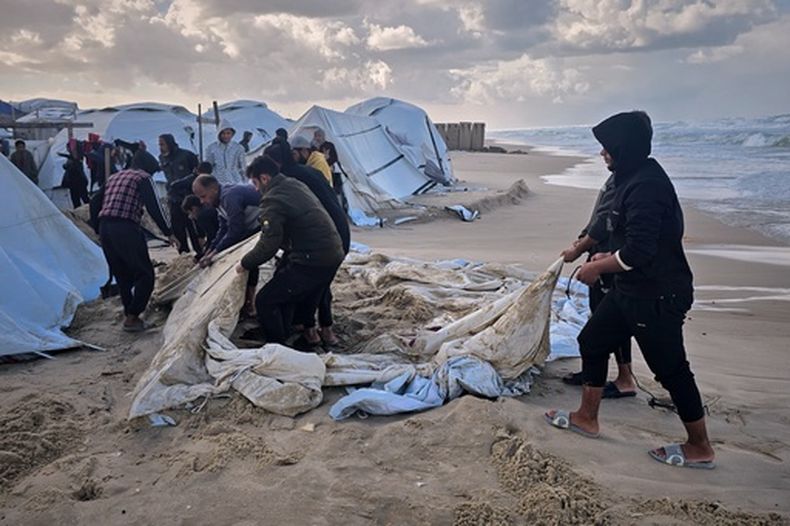 Palestinos intentan recuperar sus tiendas después de que las lluvias nocturnas inundaran su campamento junto a la playa en Jan Yunis, en el sur de la Franja de Gaza, el domingo 28 de diciembre de 2025. (AP Foto/Mohammad Jahjouh)
