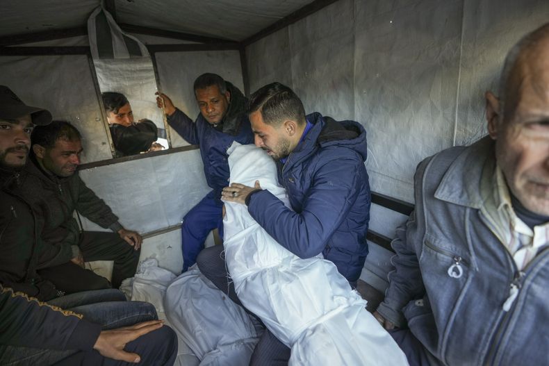 Mohammad Eid lleva el cuerpo de uno de sus tres familiares muertos el sábado en un ataque aéreo israelí mientras preparan el funeral en Deir al-Balah, centro de la Franja de Gaza, el domingo 12 de enero de 2025. (AP Foto/Abdel Kareem Hana)