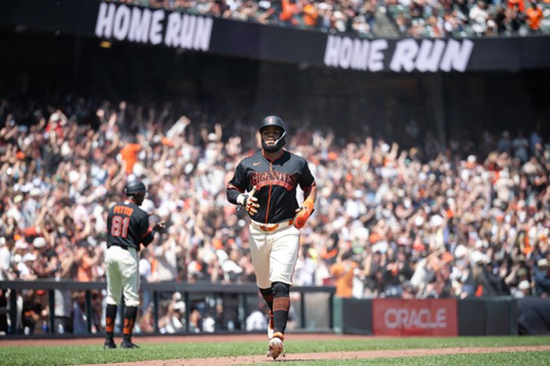 Heliot Ramos, derecha, de los Gigantes de San Francisco, corre rumbo al plato después de que su compañero Casey Schmitt bateara un jonrón de tres carreras en la sexta entrada del juego de béisbol de Grandes Ligas contra los Rockies de Colorado, el sábado 11 de julio de 2026, en San Francisco. (AP Foto/Thien-An Truong)