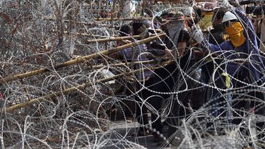 americateve | Manifestanes antigubernamentales usan una escalera para tratar de quitar el alambre de p&uacute;as colocado a la entrada de las oficinas de la primera ministra en  Bangkok, Tailand&iacute;a, el jueves 12 de diciembre de 2013. (Foto AP/Sakchai Lalit)