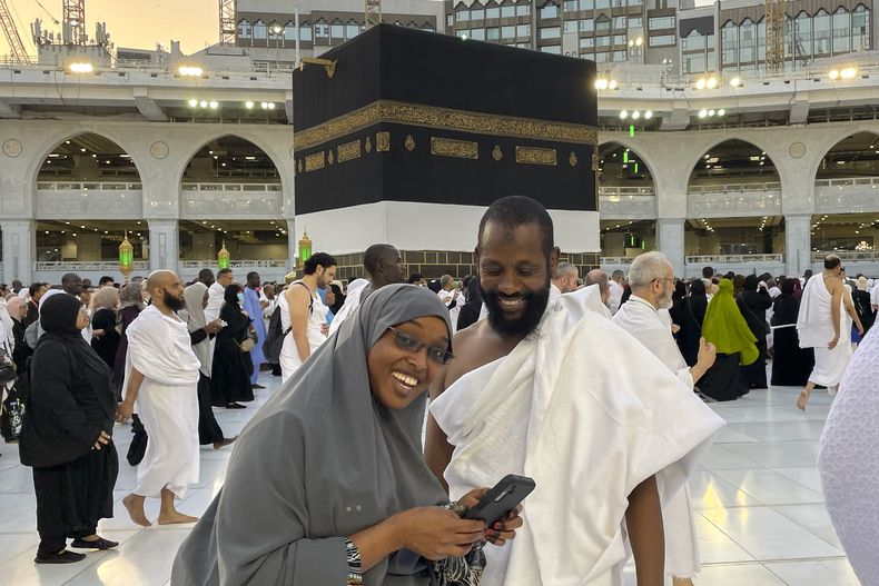 Peregrinos somalíes se preparan para tomarse una selfi ante la Kaaba, el edificio cúbico en la Gran Mezquita de La Meca, durante el peregrinaje anual del haj, en Arabia Saudí, el lunes 26 de junio de 2023. (AP Foto/Amr Nabil)