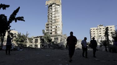 americateve | Palestinos caminan frente al derruido edificio conocido como el Complejo Italiano en Ciudad de Gaza el 26 de agosto del 2014. El primer ministro israel&iacute; Benjamin Netanyahu declar&oacute; el mi&eacute;rcoles 27 de agosto que Israel gan&oacute; la gu