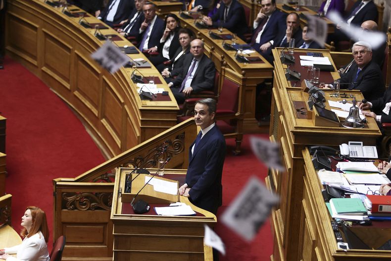 ARCHIVO – Manifestantes arrojan volantes mientras el primer ministro griego Kyriakos Mitsotakis habla en el debate sobre la moción de censura contra el gobierno conservador, en el Parlamento, en relación con un mortal desastre ferroviario ocurrido hace casi dos años, en Atenas, Grecia, el viernes 7 de marzo de 2025. (Ismini Vlassopoulou/InTime News vía AP, Archivo)