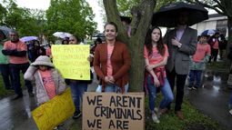 ARCHIVO – Un grupo de personas escuchan a un orador en un mitin del grupo activista Iowa Movement for Migrant Justice el miércoles 1 de mayo de 2024, en Des Moines, Iowa. El letrero en primer plano dice: No somos criminales. Somos trabajadores que laboran duro. (AP Foto/Charlie Neibergall, Archivo)