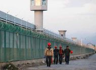 Trabajadores caminan por el perímetro de lo que el régimen chino llama campo de educación vocacional, pero que es ampliamente considerado como un campo de concentración y trabajo forzado para miembros de la minoría Uigur. Foto: REUTERS/Thomas Peter