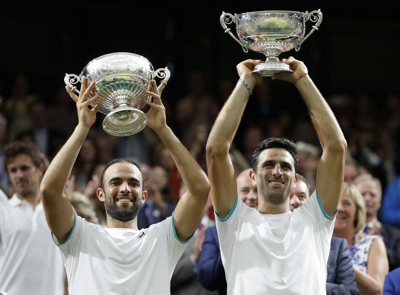 ARCHIVO - Los colombianos Juan Sebastián Cabal (izquierda) y Robert Farah levantan el trofeo de dobles de Wimbledon, el 13 de julio de 2019 (AP Foto/Kirsty Wigglesworth, archivo)